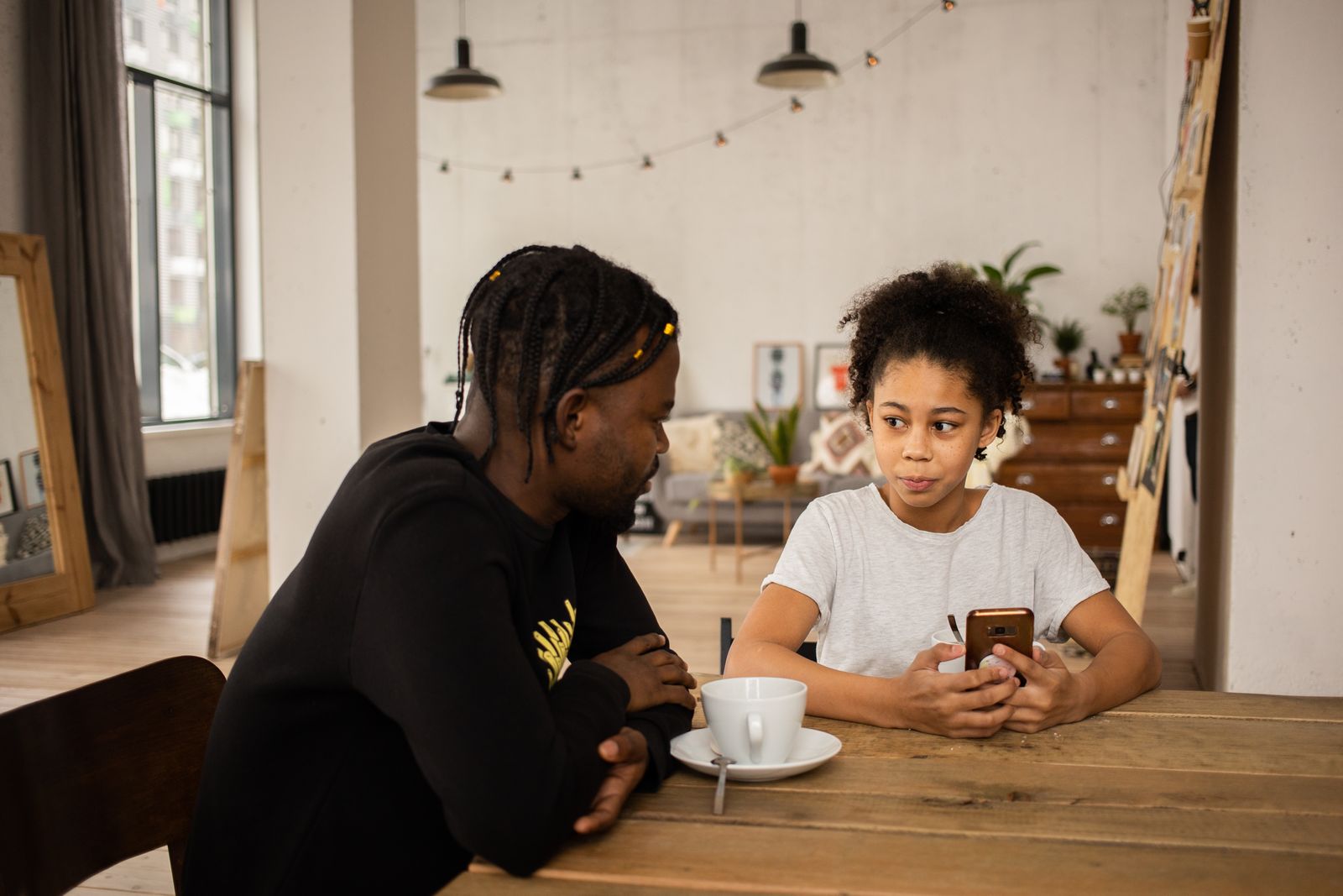 Father and young daughter sitting across from each other at a kitchen table having a conversation