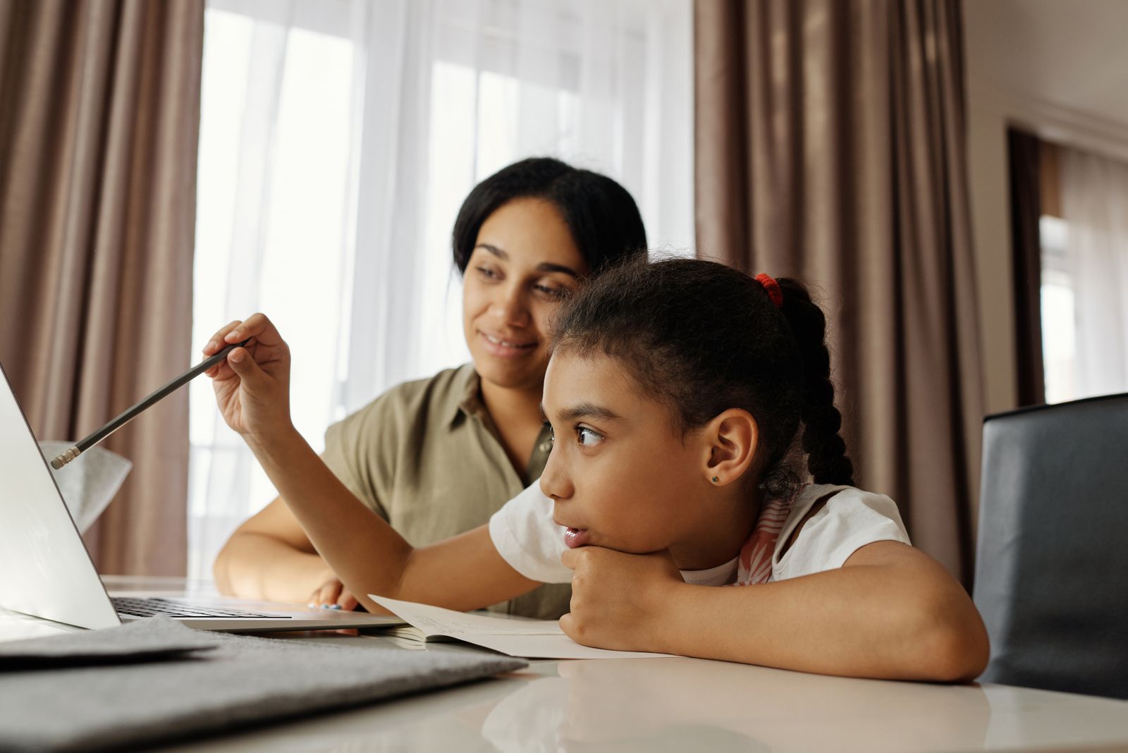 Mother and daughter sitting together at a table with a notebook and laptop working on a learning plan