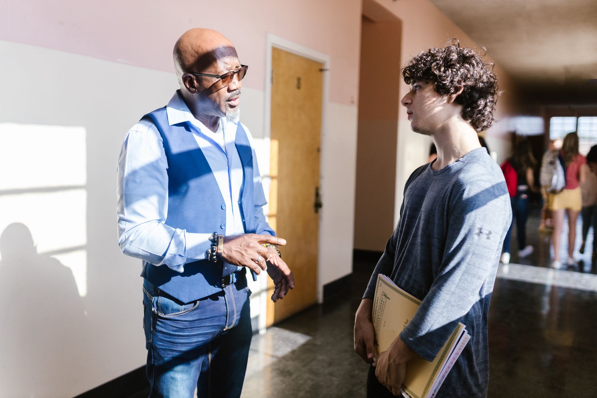 Teacher in glasses talking with a parent in a school hallway